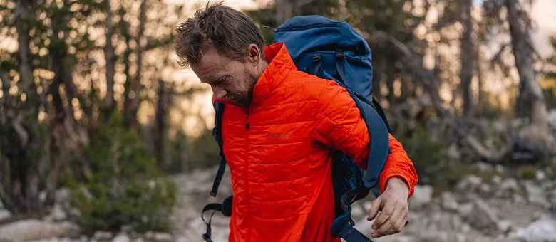 Outdoor-Imagebild - Person mit orangefarbener Fleecejacke setzt sich einen blauen Rucksack auf.