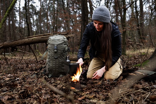 Person im Wald beim Bushcrafting an einem Lagerfeuer