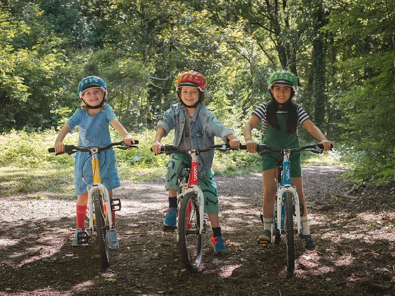 Outdoor Imagebild - drei Kinder auf Woom Bikes in gelb, rot und blau